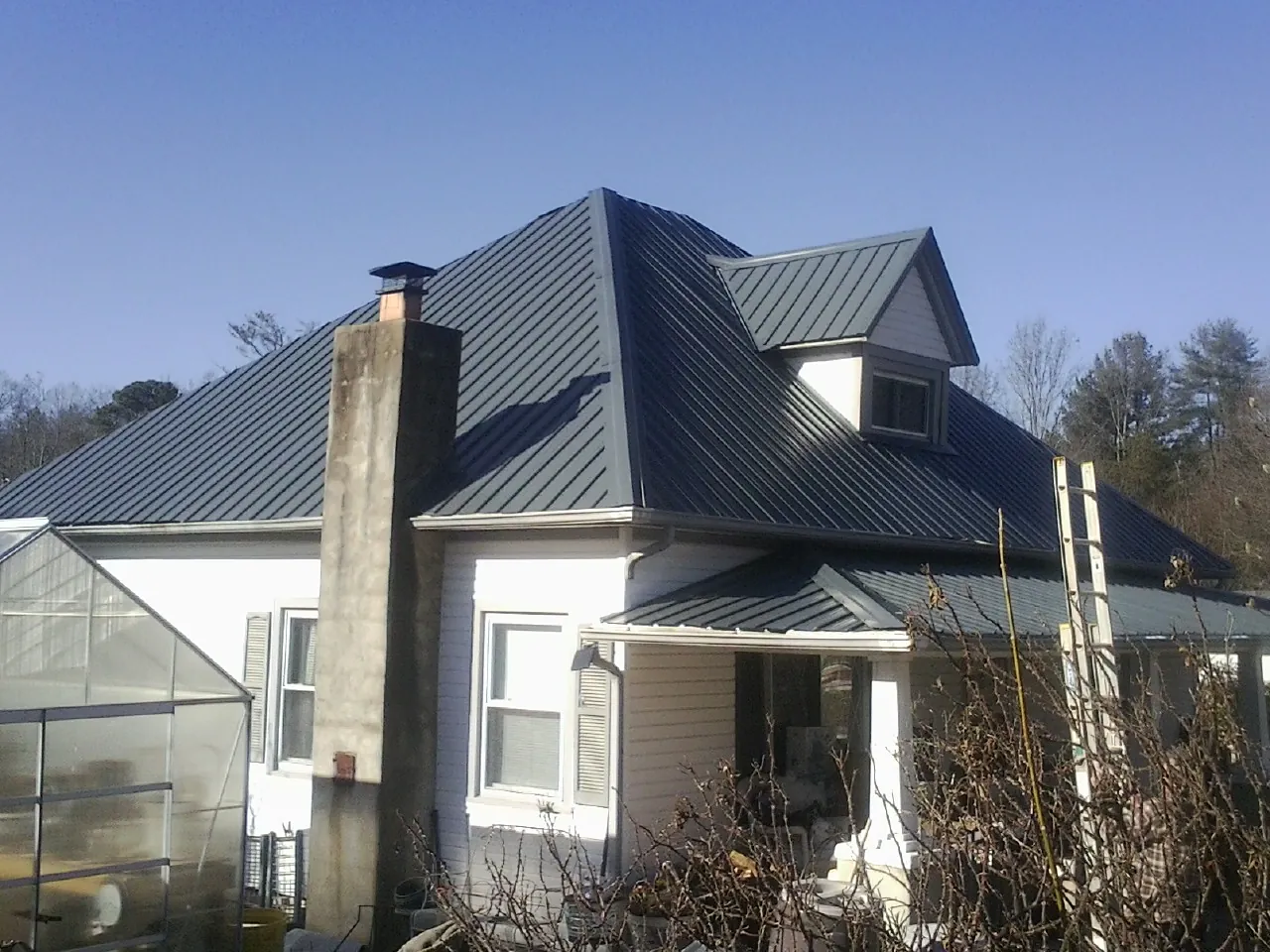 Dark blue standing seam metal roof on a white farmhouse with dormer — Slate & Tile Roof Repair by Roofing Brothers in Toms River