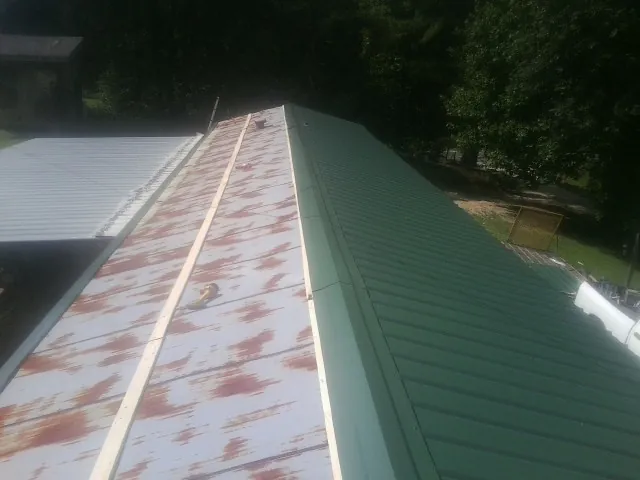 Old rusted panels beside newly installed green metal roofing — Wind Damage Roof Repair by Roofing Brothers in Toms River