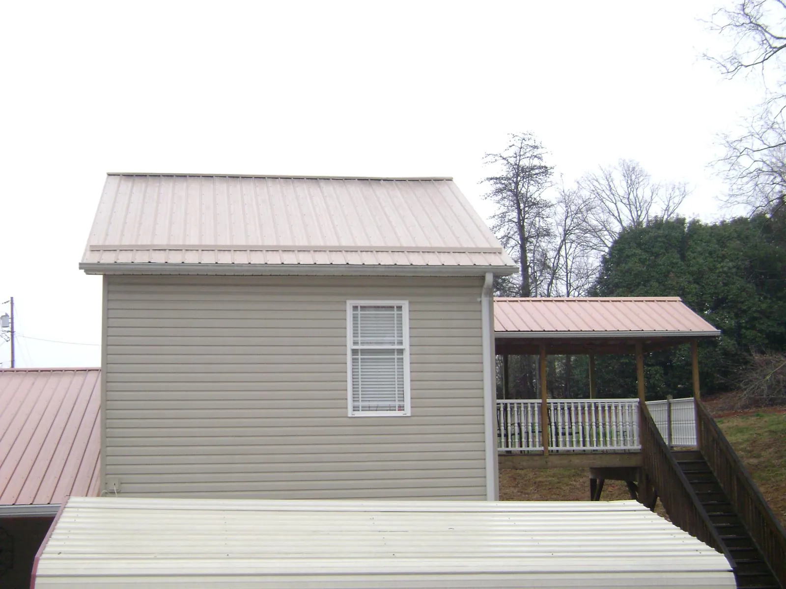 Tan metal roofs on a two story addition and attached porch, from a Roof Replacement job in Toms River