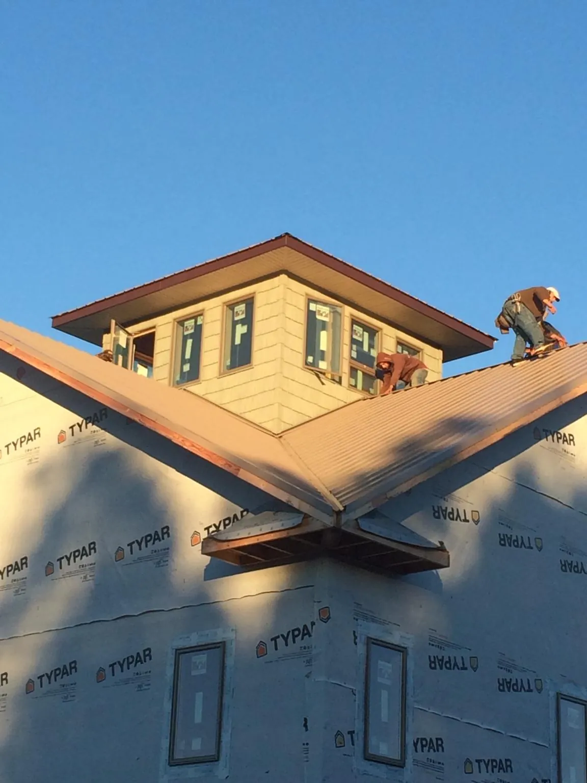 Roofers working around a rooftop cupola on a new metal roof at sunset — Roof Waterproofing in Toms River by Roofing Brothers